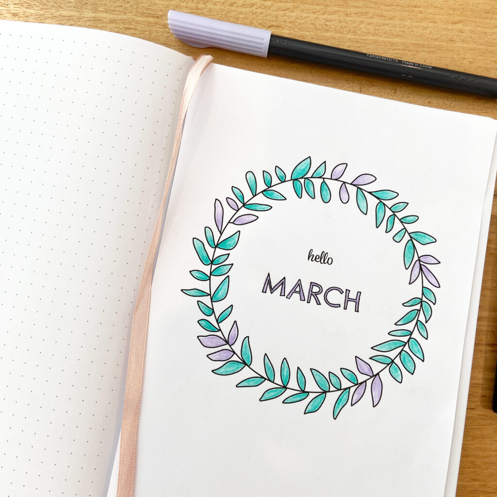 Dot grid notebook open to page with printable March journal cover attached