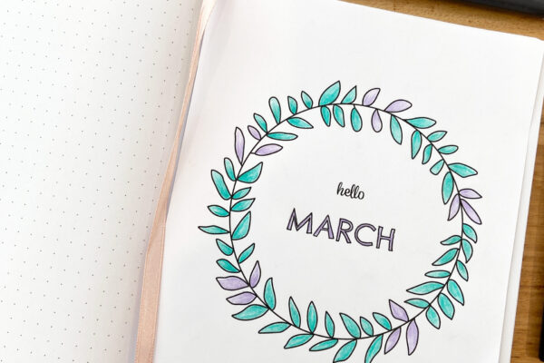 Dot grid notebook open to page with printable March journal cover attached