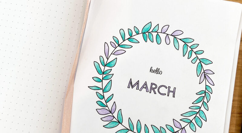 Dot grid notebook open to page with printable March journal cover attached