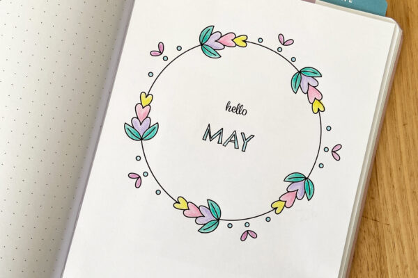 Floral hand drawn wreath-style May monthly cover page inside a bullet journal notebook to mark the beginning of the month.