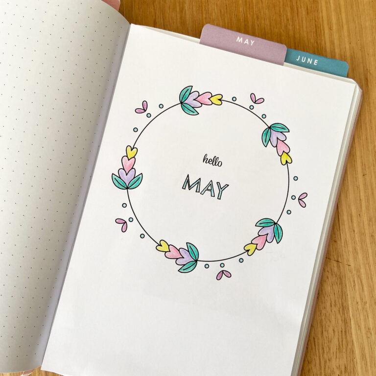 Floral hand drawn wreath-style May monthly cover page inside a bullet journal notebook to mark the beginning of the month.