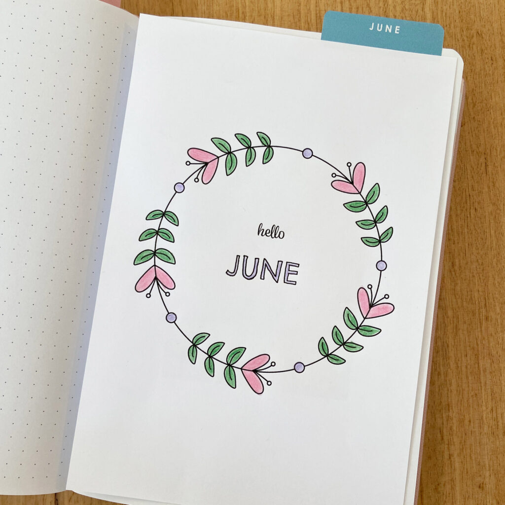 Bullet journal notebook with the June monthly cover coloured in and added to the inside page.