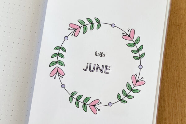 Bullet journal notebook with the June monthly cover coloured in and added to the inside page.