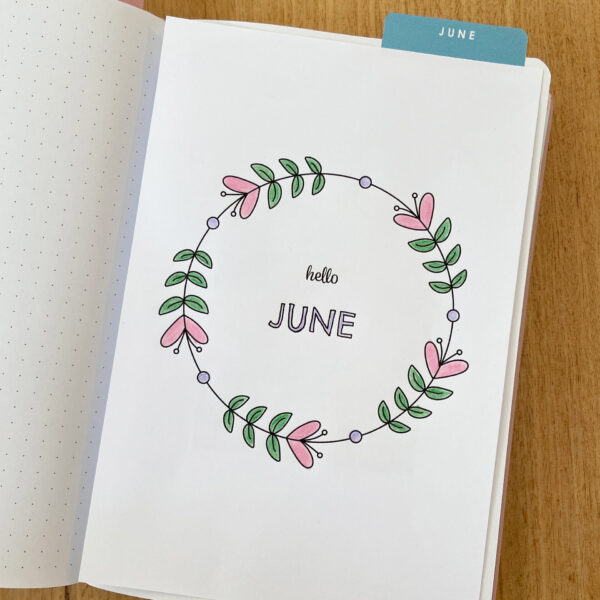 Bullet journal notebook with the June monthly cover coloured in and added to the inside page.